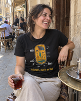 T-shirt Nefertari nera indossata in un caffè al Cairo — ambientazione generata con AI